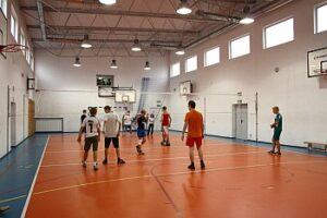 Ludzie grający w siatkówkę na pomarańczowym boisku w budynku